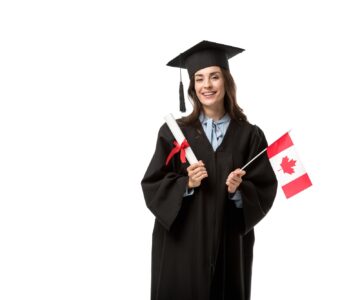 female student in academic gown looking at camera and holding canadian flag with diploma isolated on